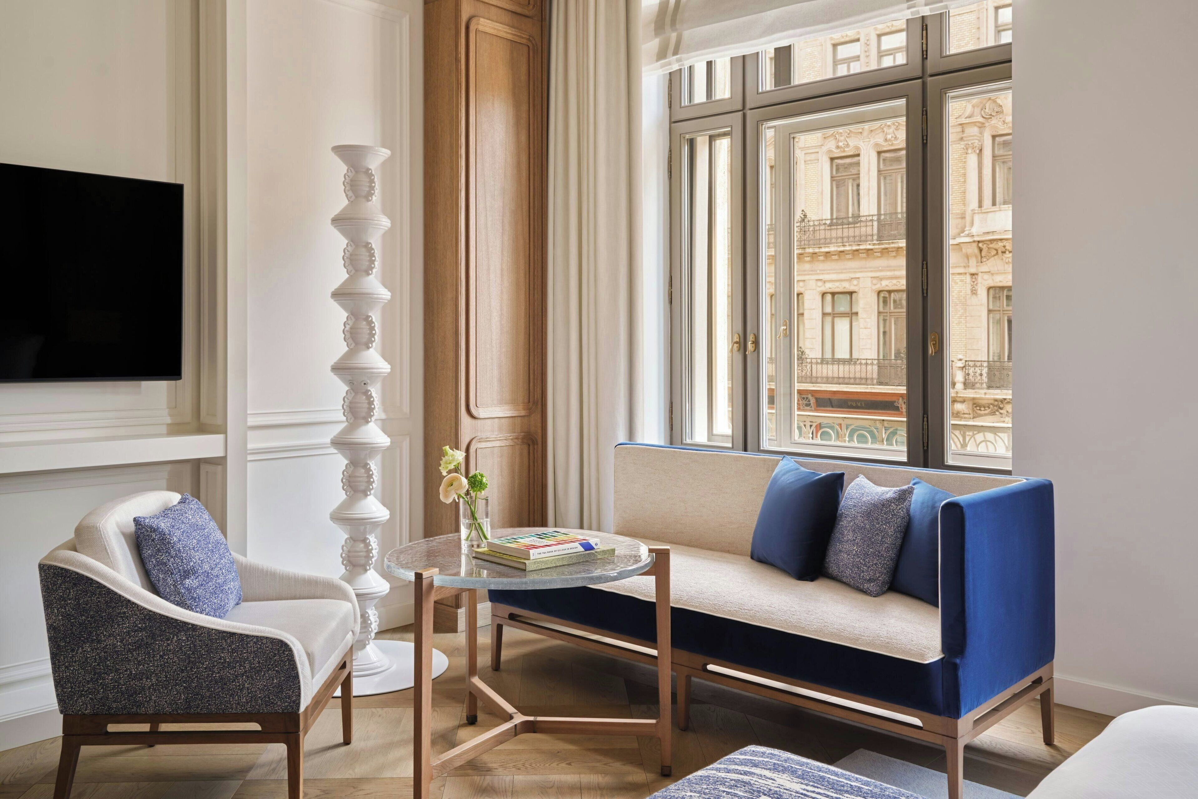 A modern living room with a sofa, armchair, and a glass coffee table.