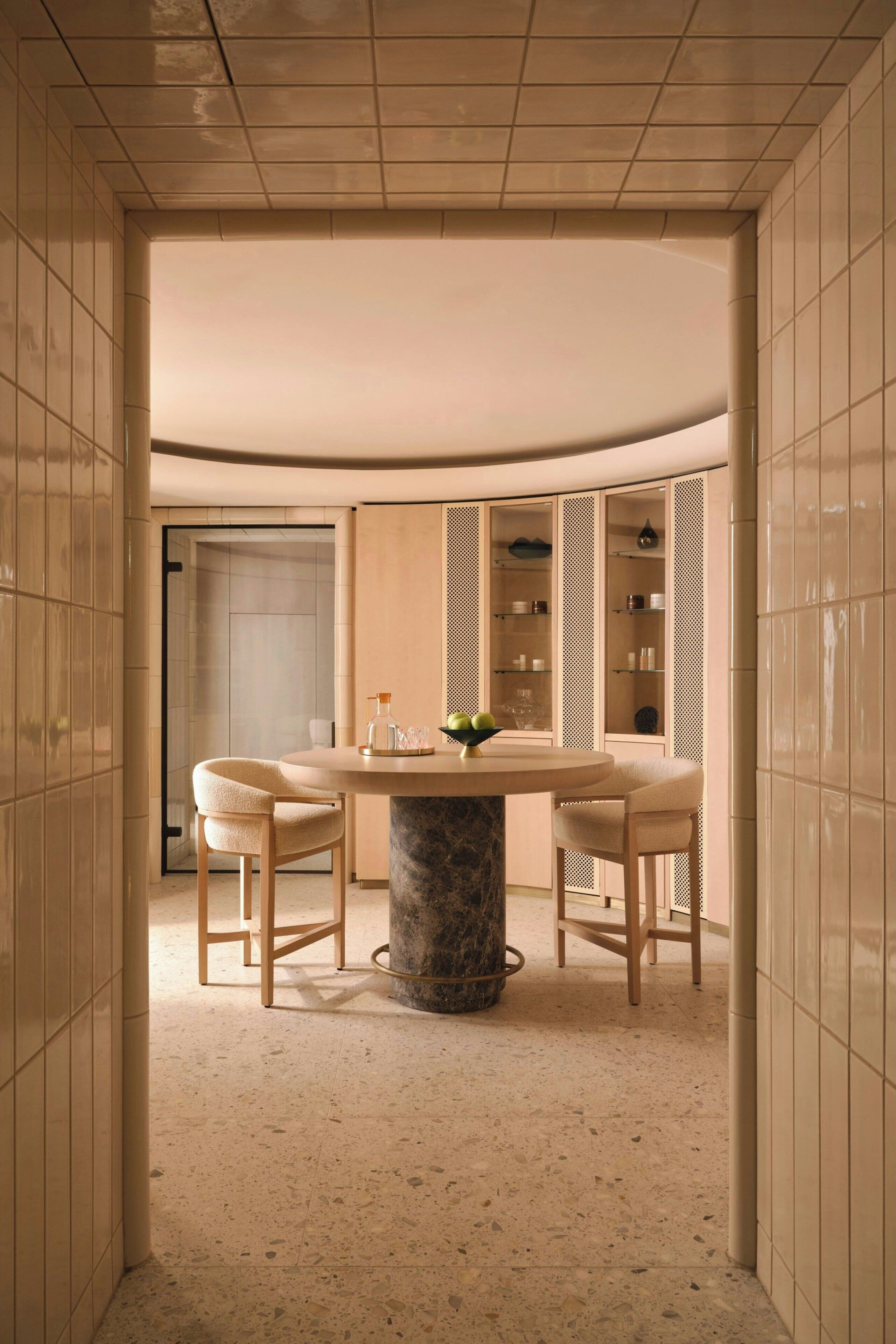A modern interior with a round table, two chairs, and a marble base.
