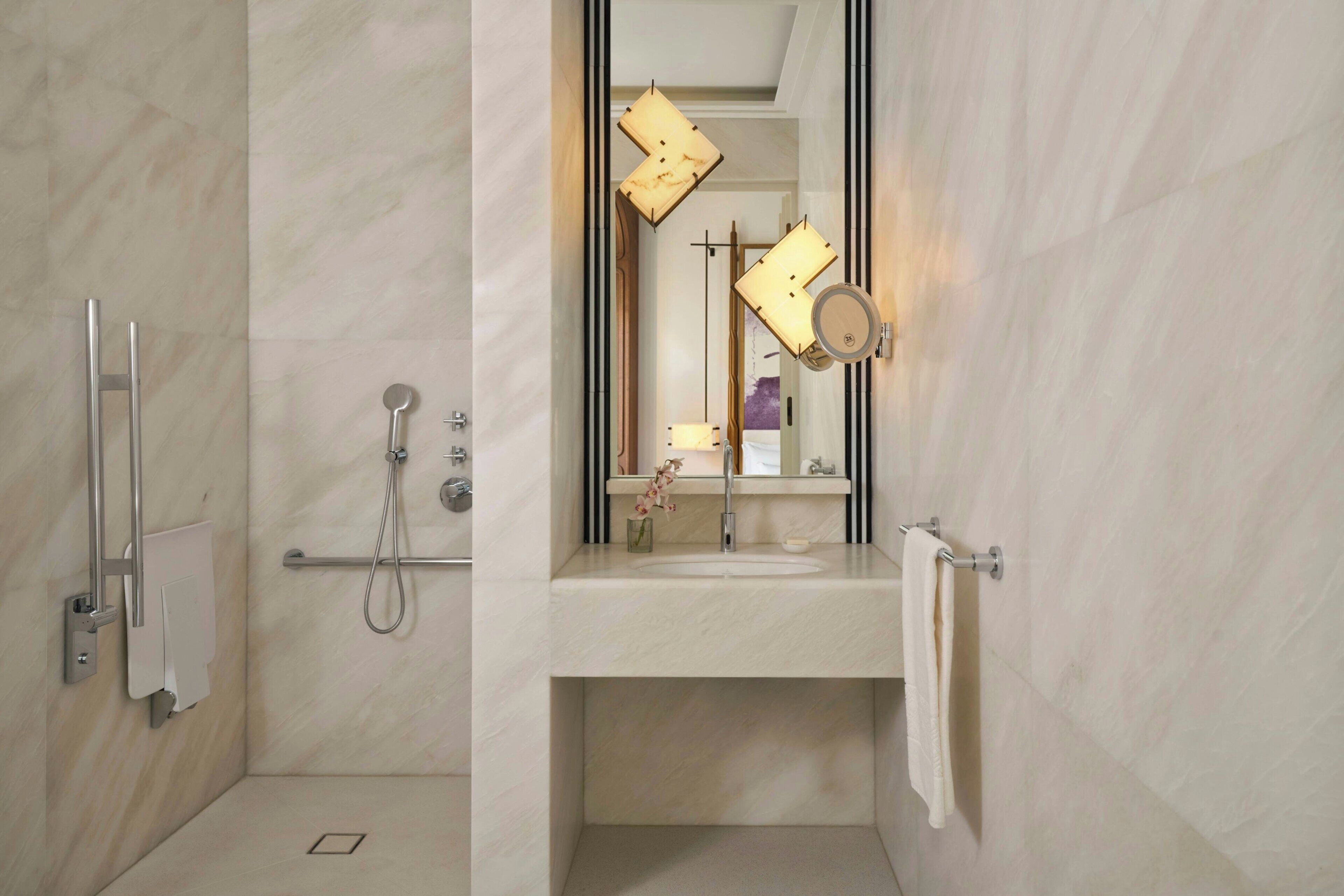 Un bany modern amb dutxa, un lavabo, un mirall i una barra de tovalloles.
