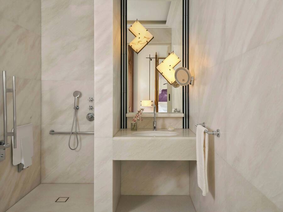 Un bany modern amb dutxa, un lavabo, un mirall i una barra de tovalloles.