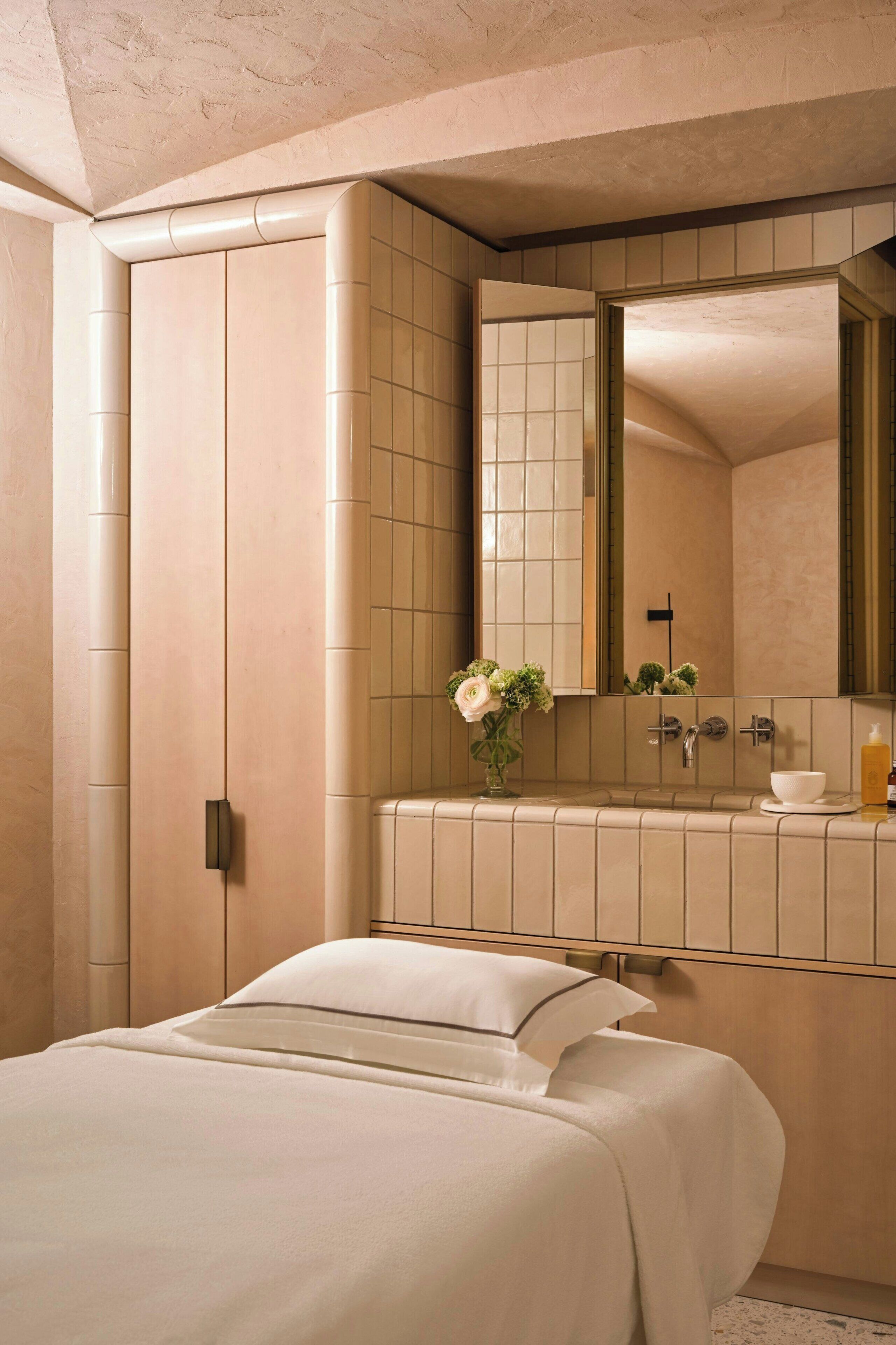 Une chambre avec un lit, une salle de bain avec un lavabo et un miroir, et un mur avec une porte.