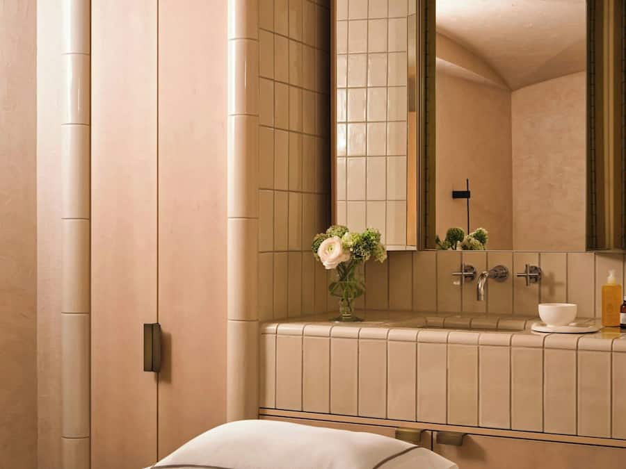 Une chambre avec un lit, une salle de bain avec un lavabo et un miroir, et un mur avec une porte.