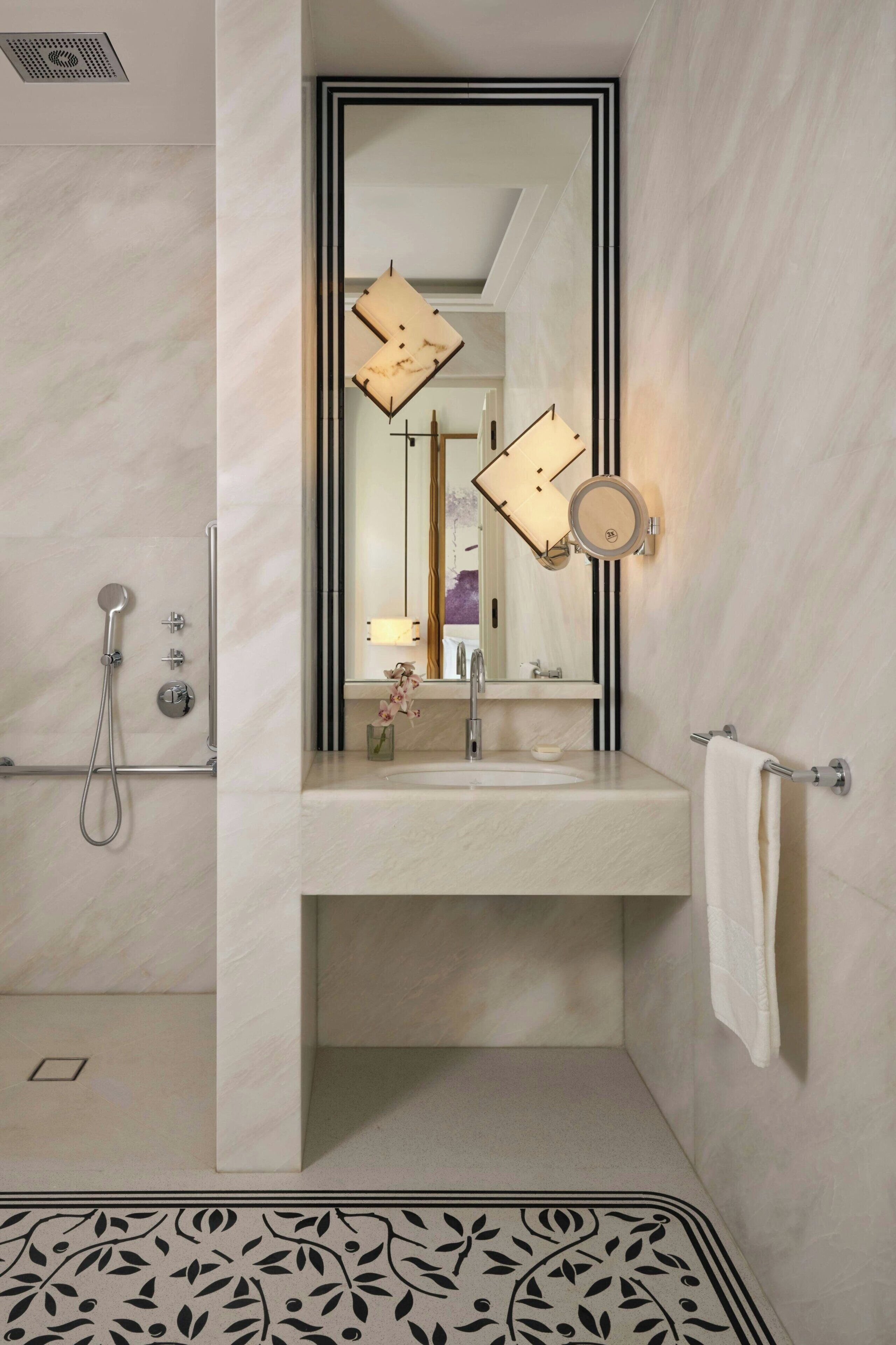 Un baño con un espejo grande, un lavabo, toallero y ducha.