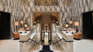 Un amplio vestíbulo con escaleras, candelabros y zonas de estar.