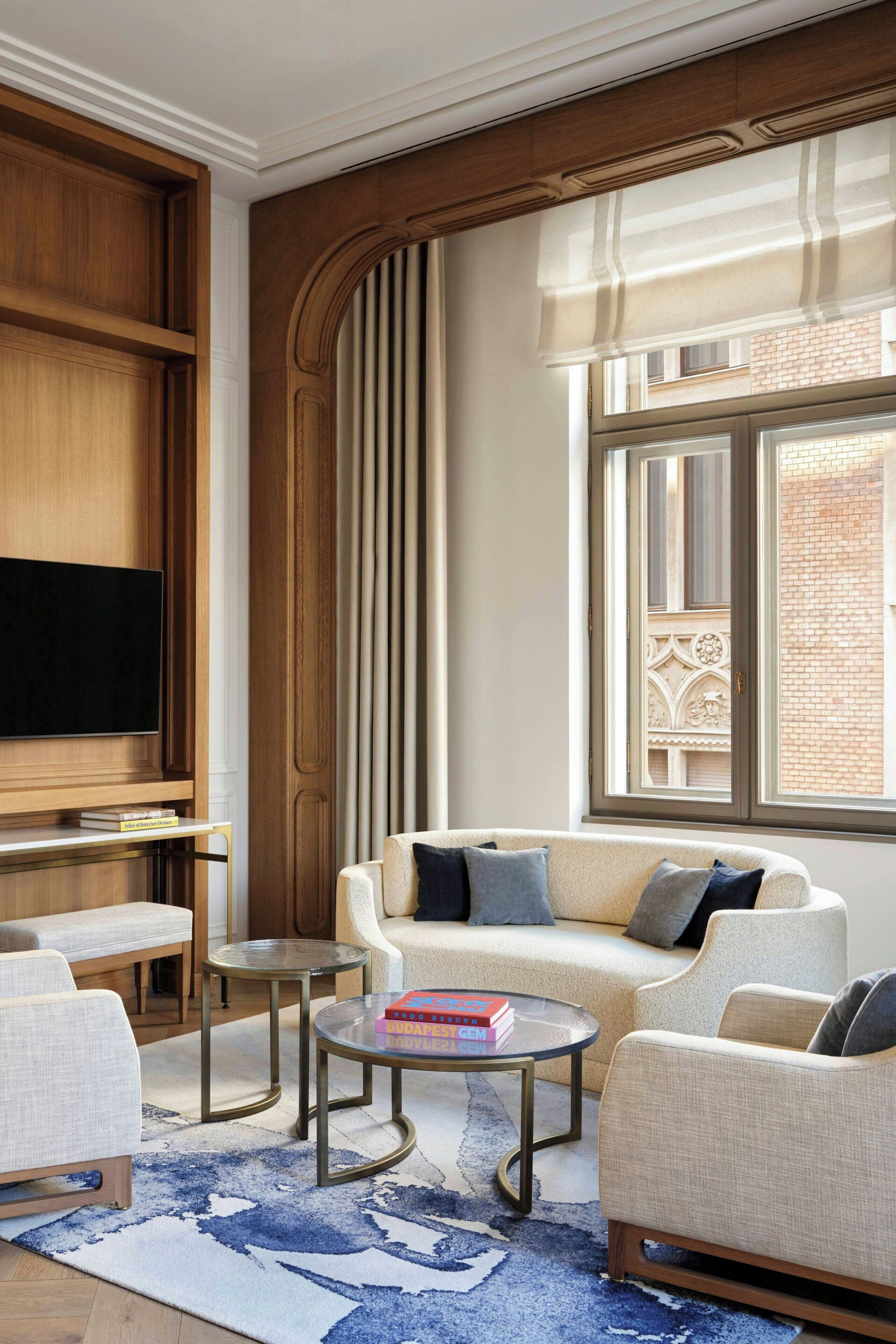 A modern living room with a sofa, coffee table, TV, and a large window with curtains.