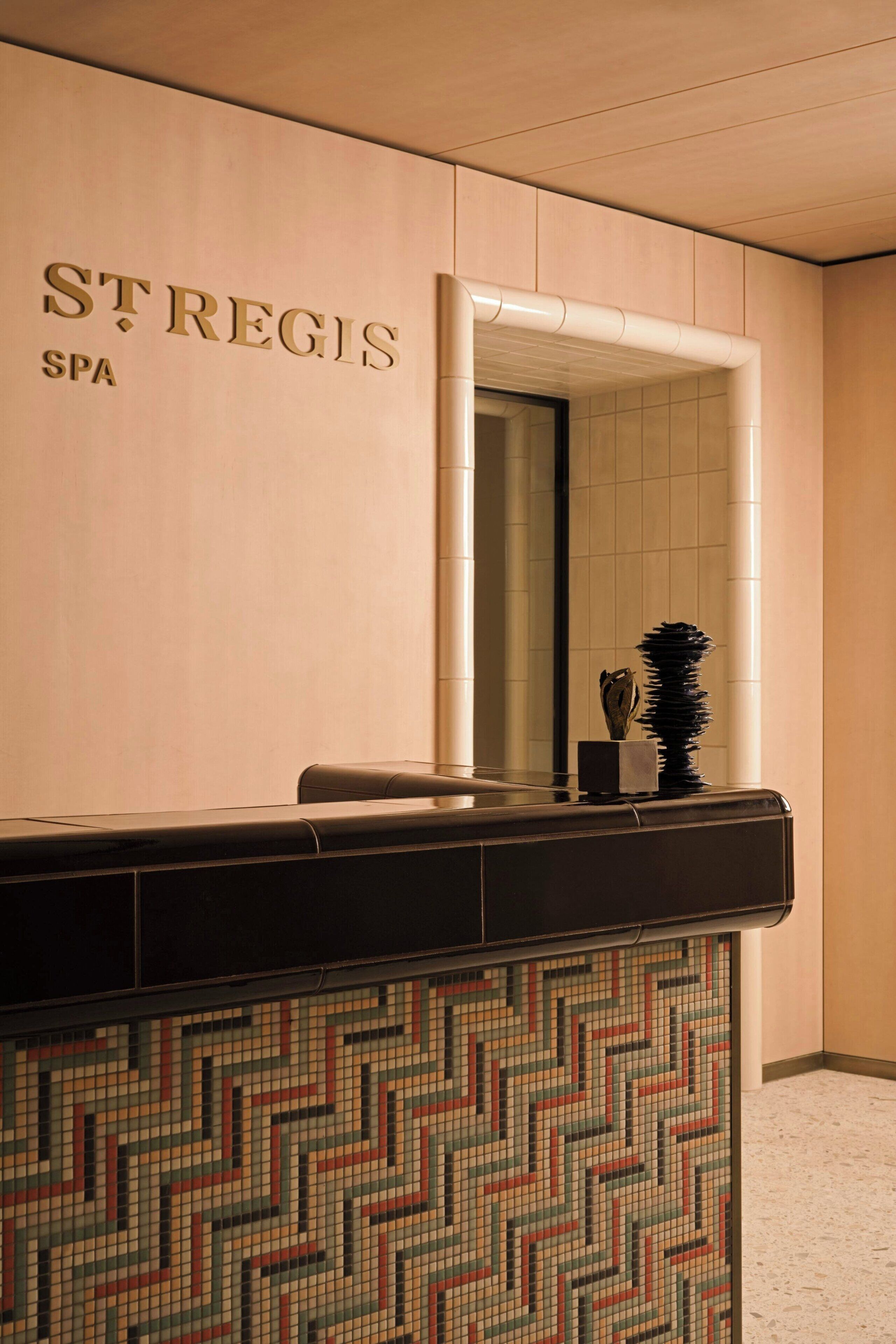 A reception area with a mirror, a reception desk, and a wall with the text 'ST. REGIS SPA'.