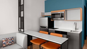 A compact kitchen with a microwave, refrigerator, and dishwasher. There is a dining area with a table and two chairs. - StudioRes by Marriott Denver Tech Center (Centennial)