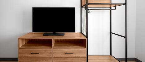 A room with a wooden desk, a black TV, and a metal shelving unit.