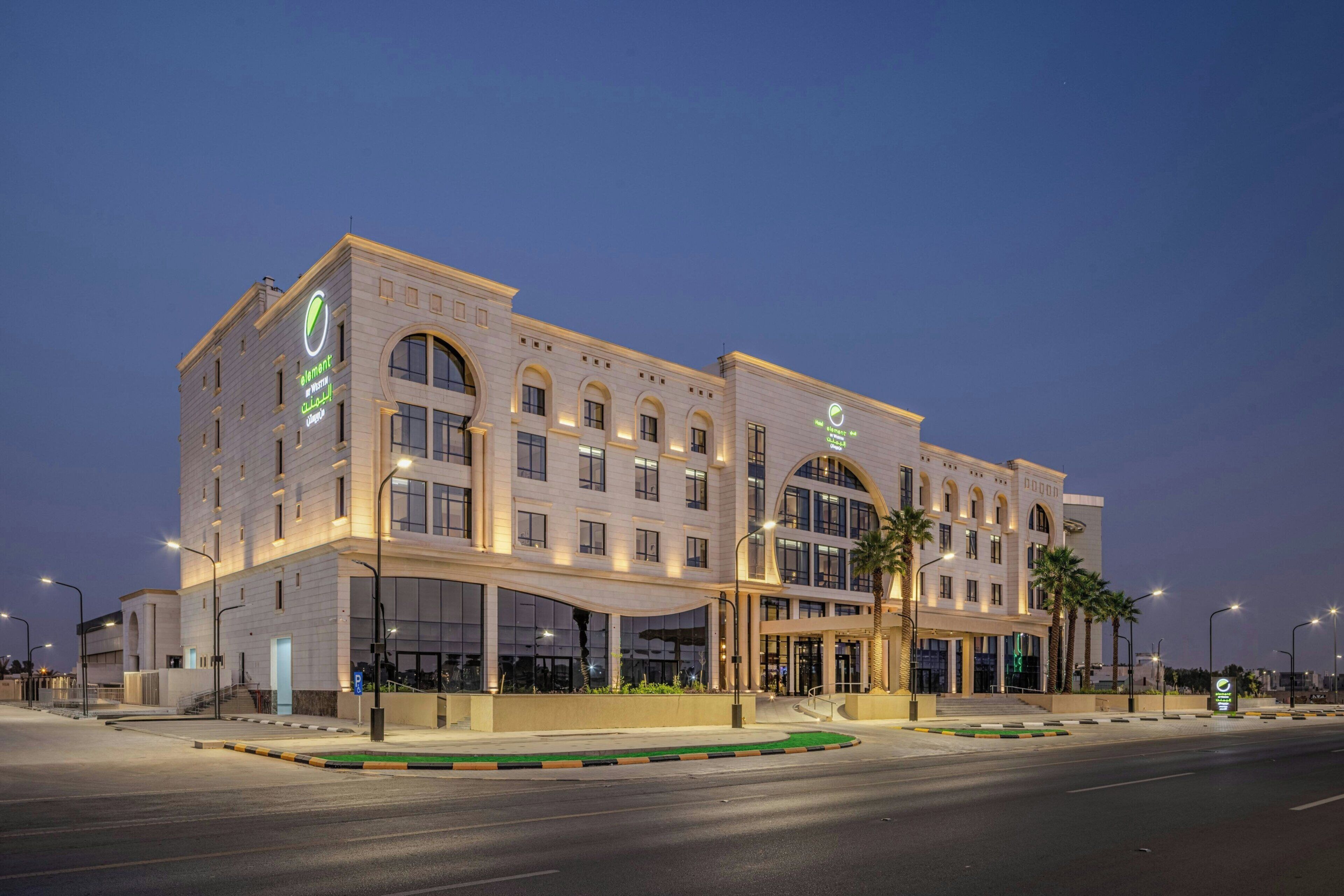 A modern hotel with a large entrance, multiple floors, and a prominent logo.