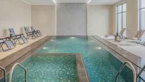 Ein Innenpool mit Liegestühlen und Fliesenboden.