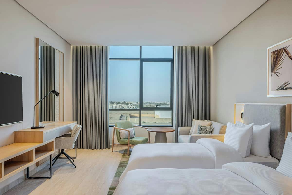 Una habitación de hotel con cama, escritorio, silla, mesita y televisor.