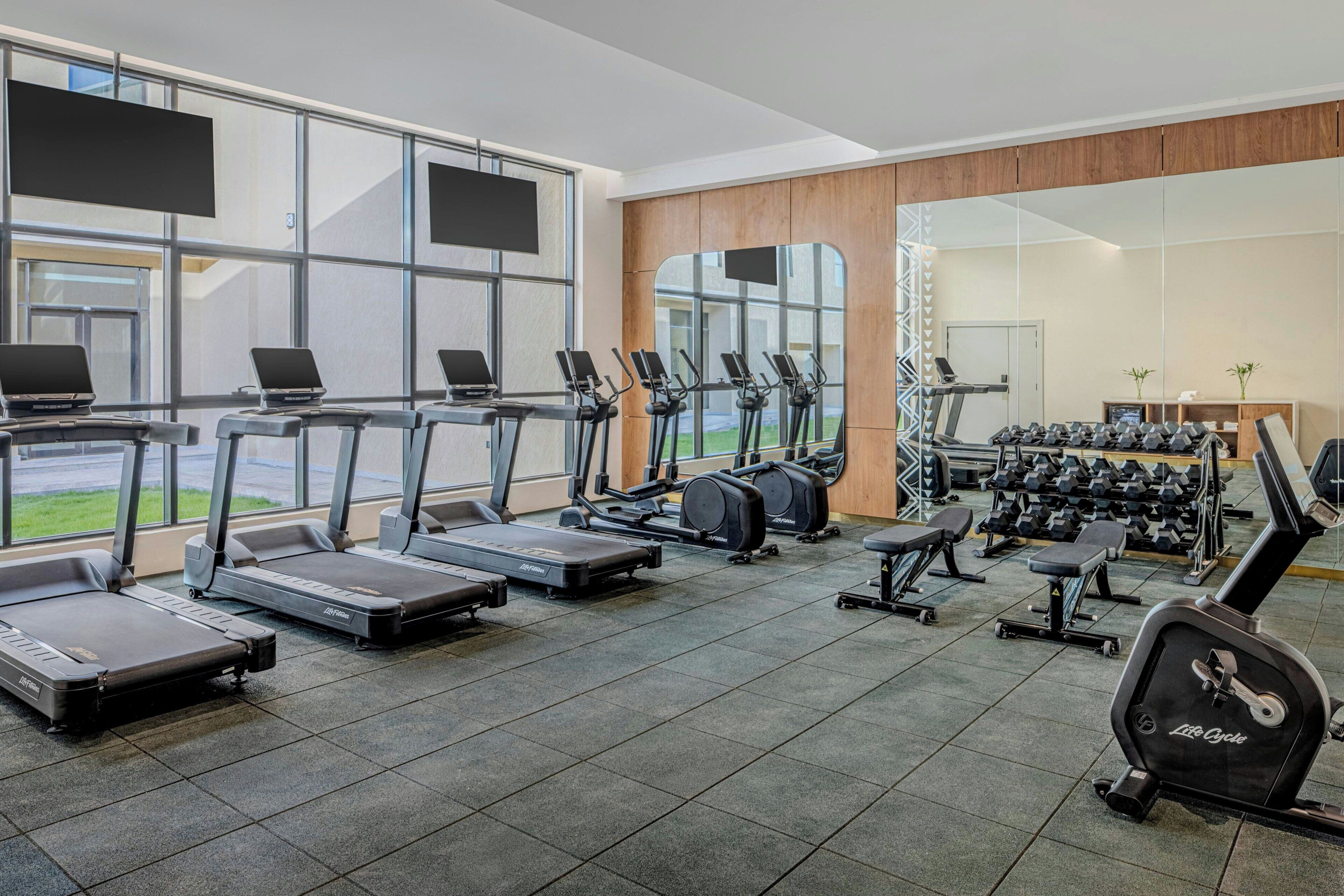 Une salle de sport équipée de tapis de course, de vélos elliptiques et de poids libres.