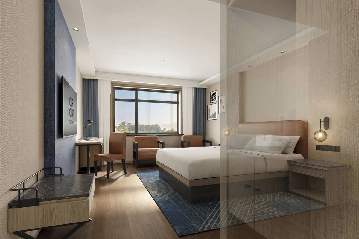 Een moderne hotelkamer met een bed, bureau, stoel en een groot raam.