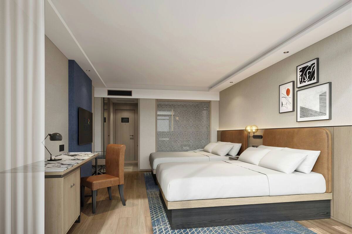 Een hotelkamer met twee bedden, een bureau, een stoel en een televisie.