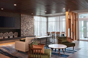 A modern lounge area with a stone wall, seating, a flat-screen TV, and large windows.