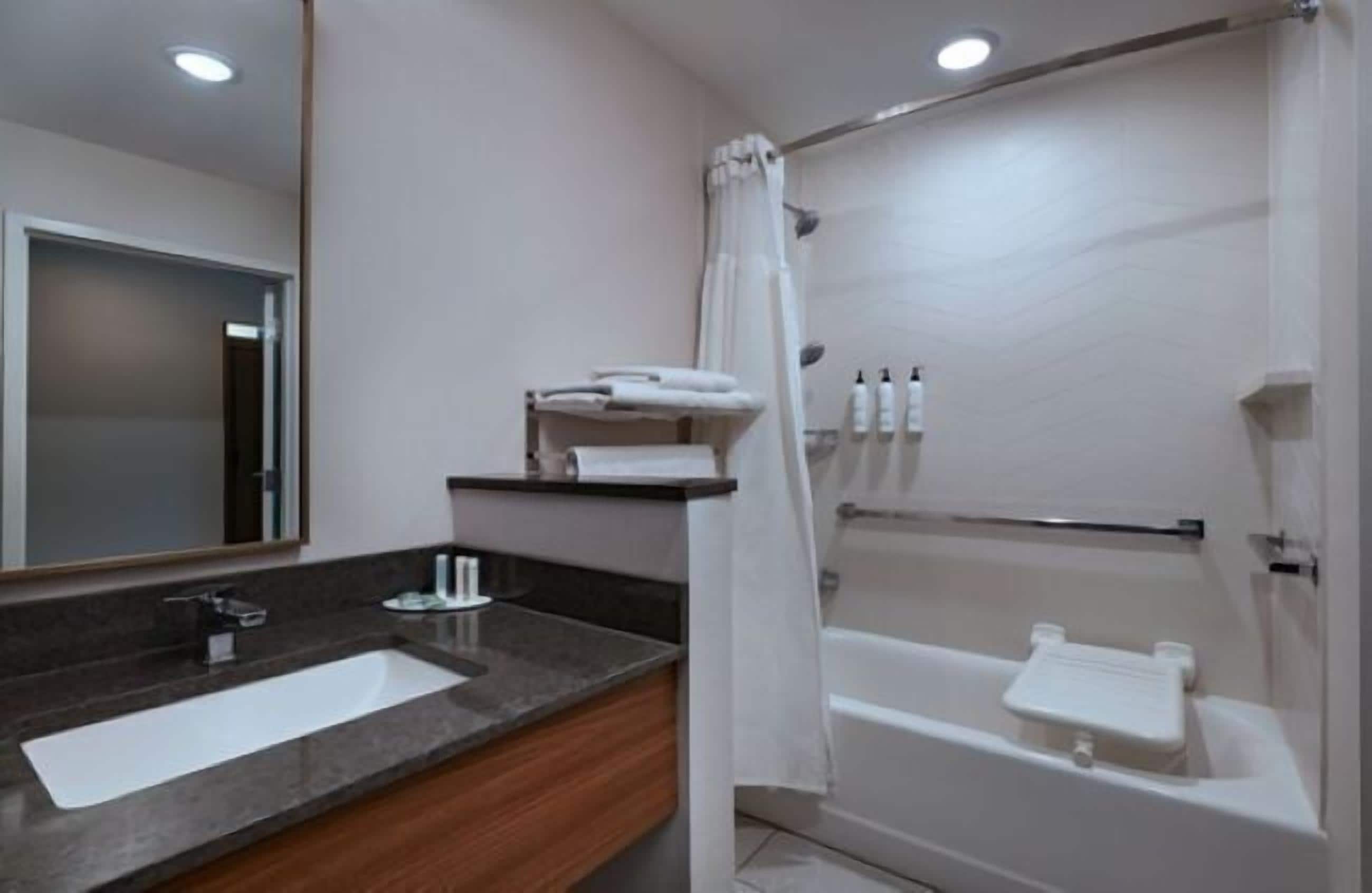A bathroom with a sink, mirror, shower, and bathtub.