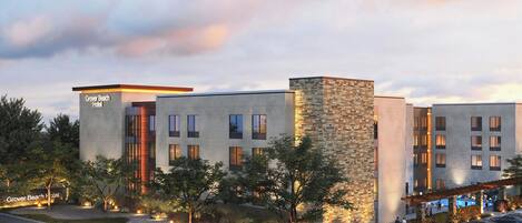 A hotel with a modern design, featuring a mix of stone and concrete facades, multiple windows, and a parking area with several cars.