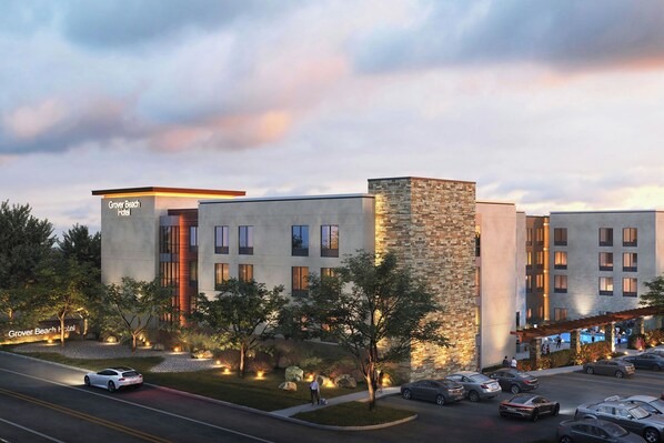 Un hotel dal design moderno, con facciate in pietra e cemento, numerose finestre e un'area parcheggio con diverse auto.