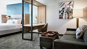 Una habitación de hotel con cama, escritorio, sofá y un cuadro en la pared.