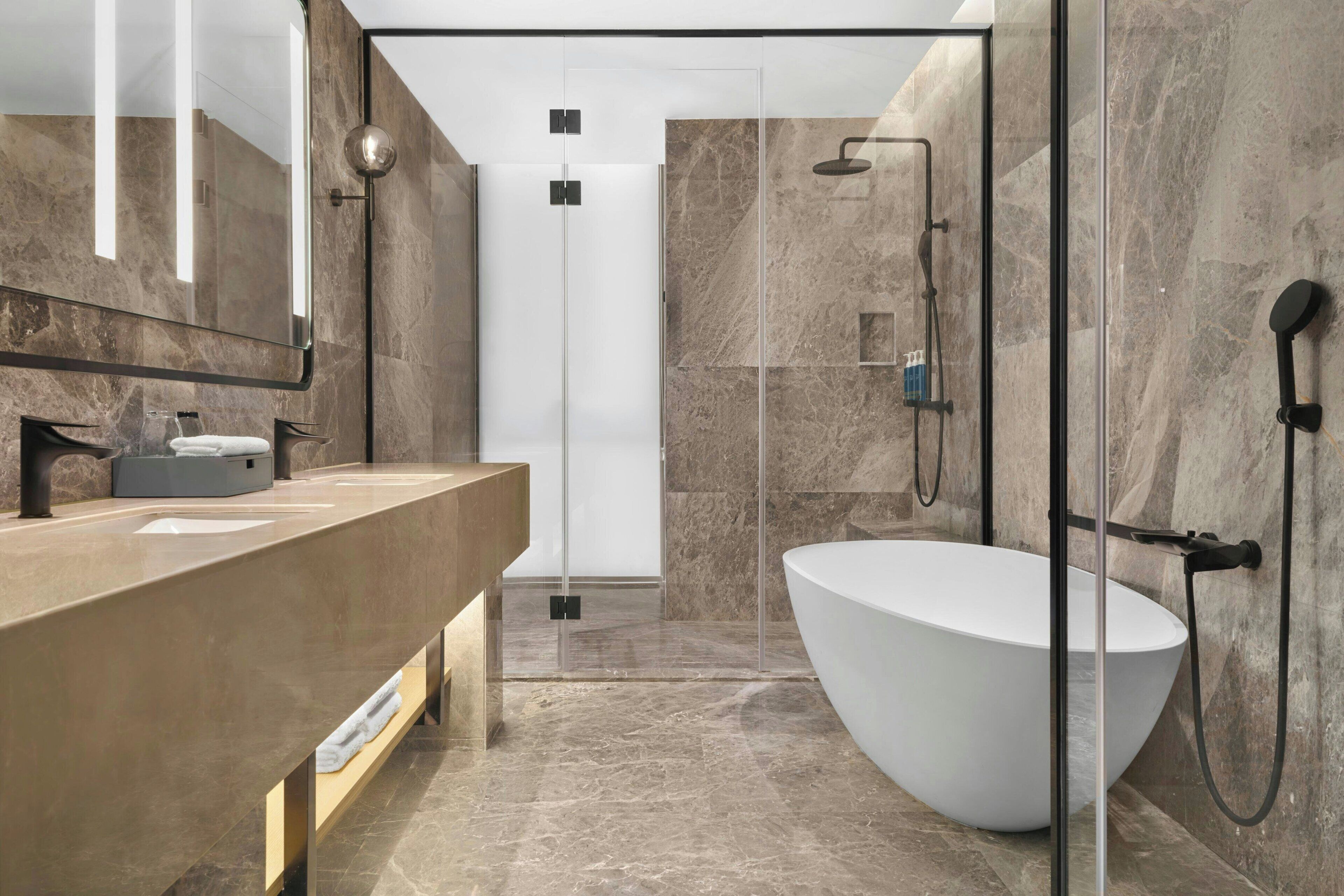 Une salle de bain moderne dotée d’une grande baignoire, d’une douche à parois de verre et d’un meuble-lavabo avec un miroir.