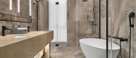 Un baño moderno con una bañera grande, un box de ducha de cristal y un tocador con espejo.