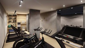 A modern gym with exercise equipment, a treadmill, and a wall-mounted shelf with exercise balls. - City Centro By Marriott Ushuaia Argentina (Ushuaia)