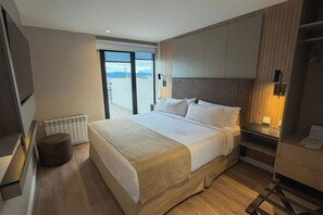 Habitación de hotel con una cama grande, una mesita de noche, un radiador y vistas al exterior.