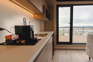 Una cocina moderna con microondas integrado, cafetera y un lavamanos pequeño.