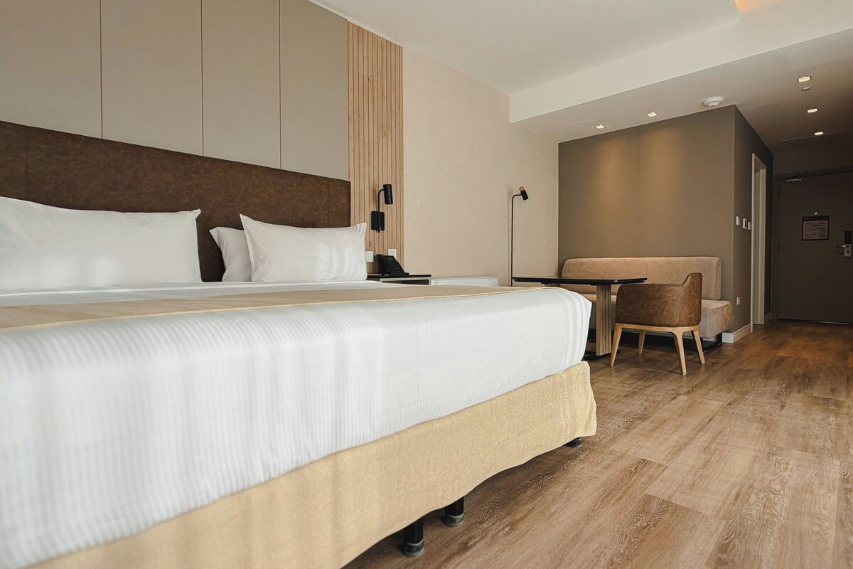 Ett modernt hotellrum med en stor säng, ett skrivbord och en stol.