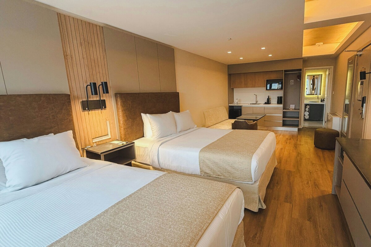 Ett hotellrum med två sängar, ett litet pentry och ett badrum.
