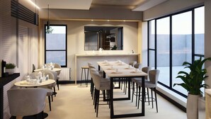 A modern dining area with a long table set for a meal, surrounded by chairs. There are multiple small tables with chairs and a large window providing a view. - City Centro By Marriott Ushuaia Argentina (Ushuaia)