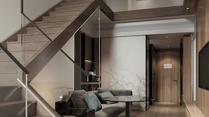 A modern interior with a wooden staircase, a glass railing, and a seating area with a glass table. - Fairfield By Marriott Hengdian (Jinhua)