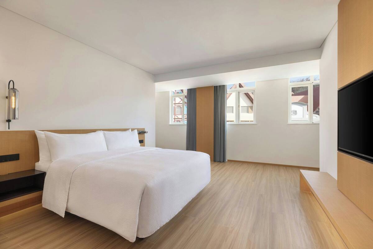 Una habitación de hotel con una cama, televisión, ventana y escalera.