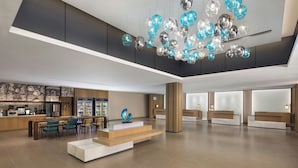 A spacious lobby with a modern reception desk, seating area, and a unique ceiling light fixture. - Fairfield By Marriott Hengdian (Jinhua)