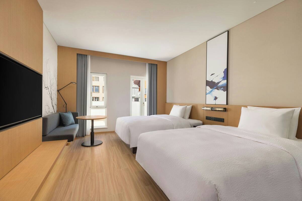 Habitación de hotel con dos camas, un sofá, un televisor y una mesita.