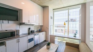 A modern kitchen with a flat-screen TV, stainless steel appliances, and a large window offering a city view. - 2210 Kenect  (Phoenix)