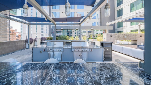 An outdoor kitchen area with a hot tub, grill, and seating. - 2210 Kenect  (Phoenix)