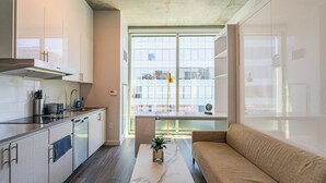 A modern kitchen with white cabinets, a built-in stove, and a dining area with a sofa and a table. - 2210 Kenect  (Phoenix)