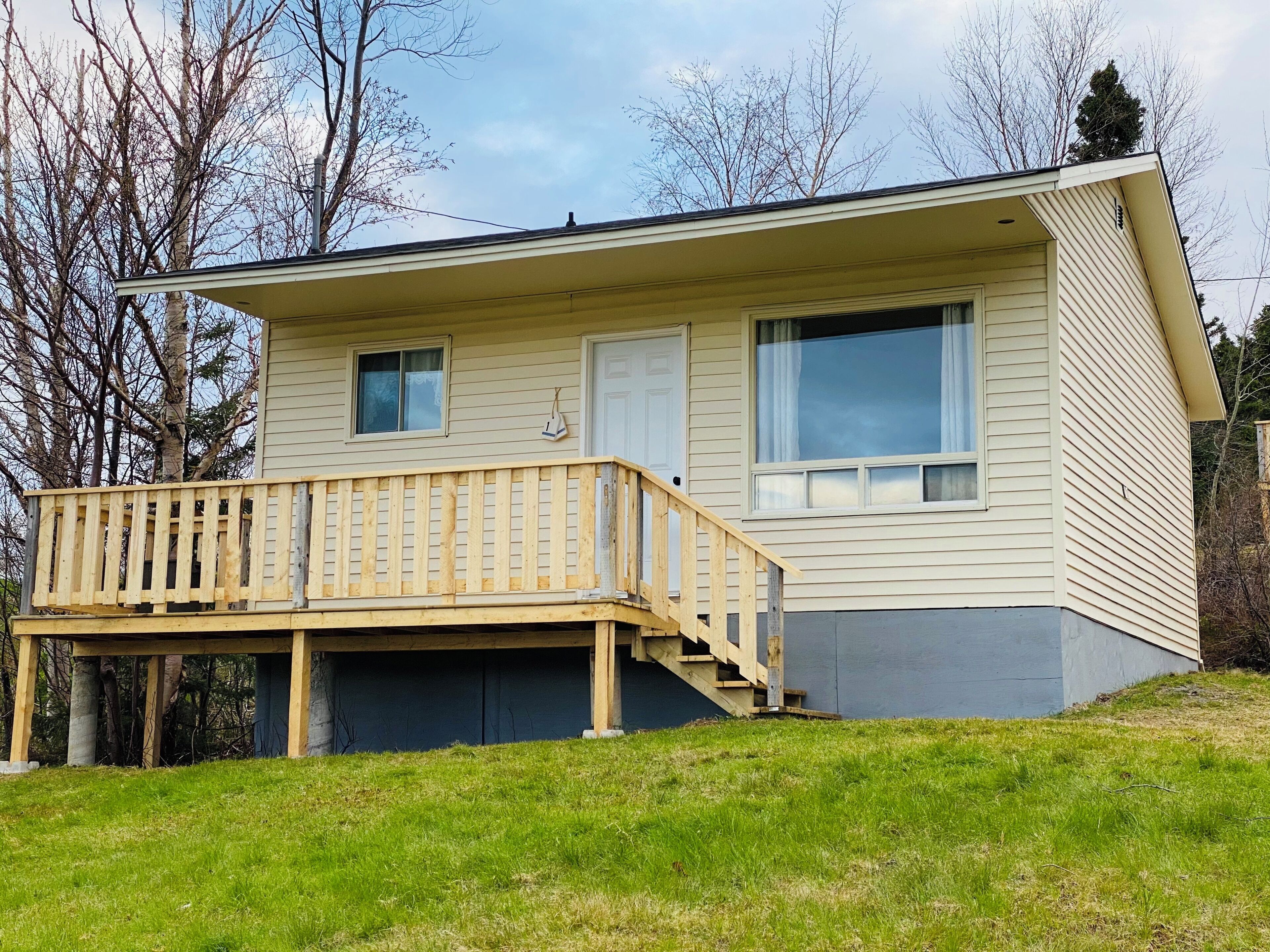 A two-story house with a wooden deck and a small staircase leading to the second floor.