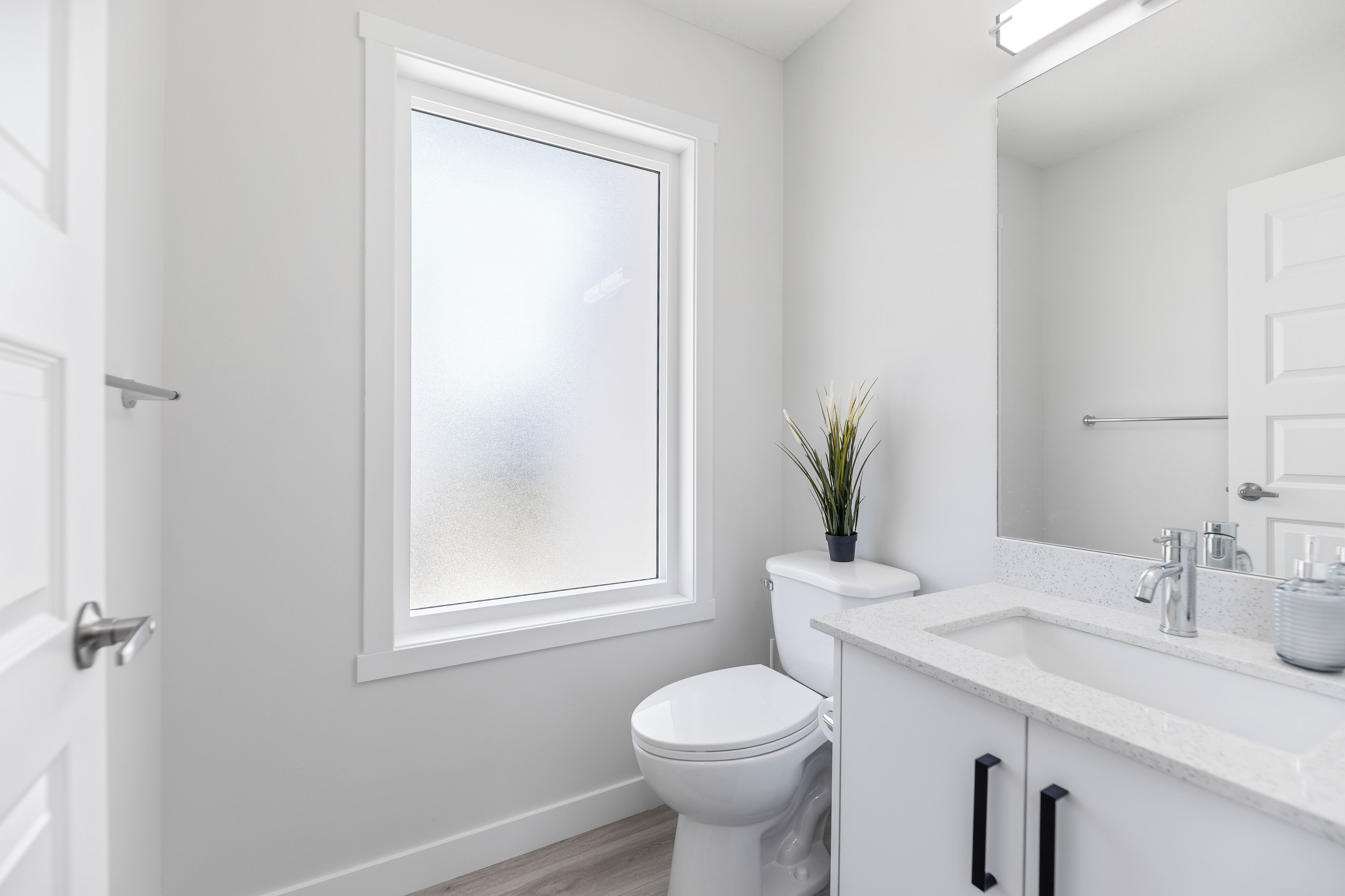Une salle de bain moderne avec des toilettes blanches, un lavabo et une fenêtre.