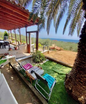 A covered outdoor area with a patio, seating, and a view of the sea.