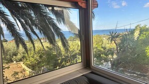 Une pièce dotée de grandes fenêtres donnant sur un jardin et la mer.
