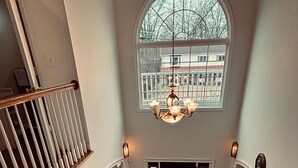 A spacious interior with a grand staircase, a large chandelier, and a view through a window. - Delightful 3-bedroom 2-bathroom Single family home in Springfield (Springfield)