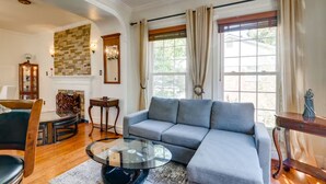 A living room with a gray sectional sofa, a glass coffee table, a fireplace, and a large window with curtains. - Delightful 3-bedroom 2-bathroom Single family home in Springfield (Springfield)
