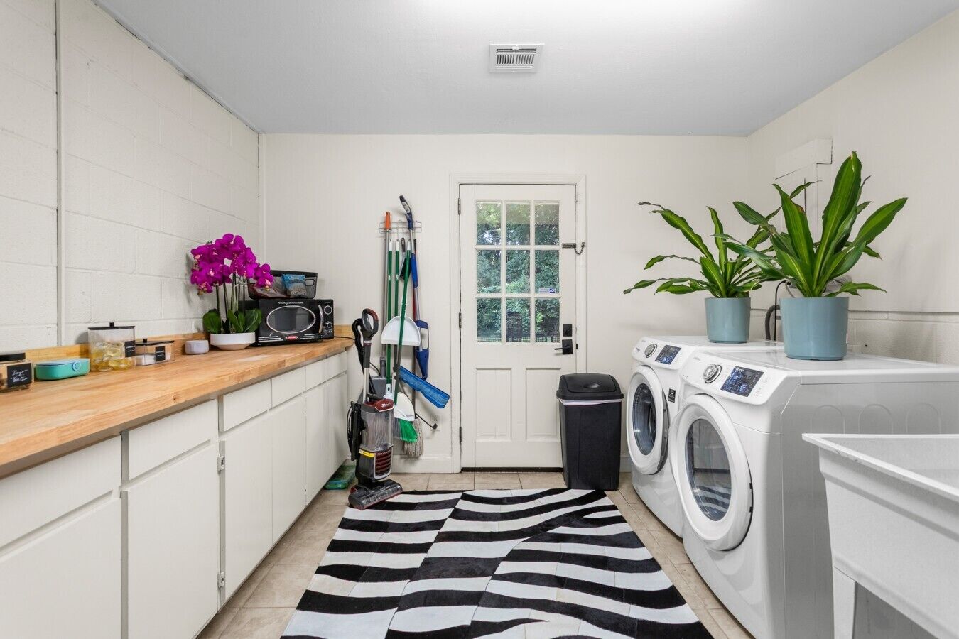 Un cuarto de lavado con lavadora, secadora, microondas y diversos productos de limpieza.