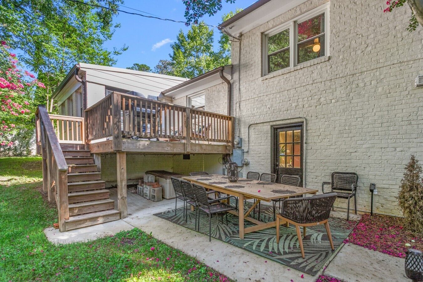 A two-story house with a balcony, a patio with a table and chairs, and a brick exterior.