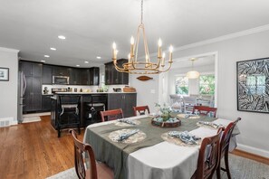 Una cocina moderna con armarios oscuros, una isla central y un comedor con una mesa dispuesta para seis comensales.