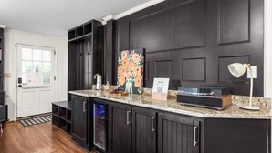 A kitchen with dark cabinetry, a granite countertop, a painting, a sign, and a built-in oven.
