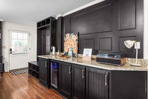 A kitchen with dark cabinetry, a granite countertop, a painting, a sign, and a built-in oven.