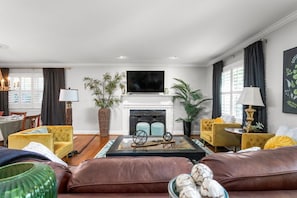 Una sala de estar moderna con chimenea, sofás amarillos, una mesa de centro y un televisor de pantalla plana.